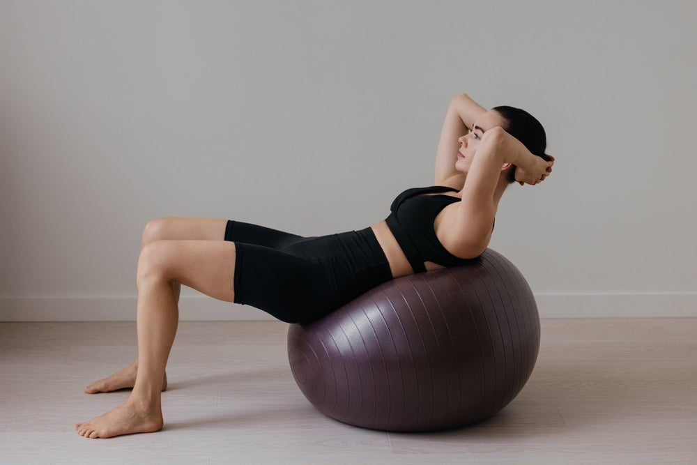 Frau trainiert mit Gymnastikball im Home Gym