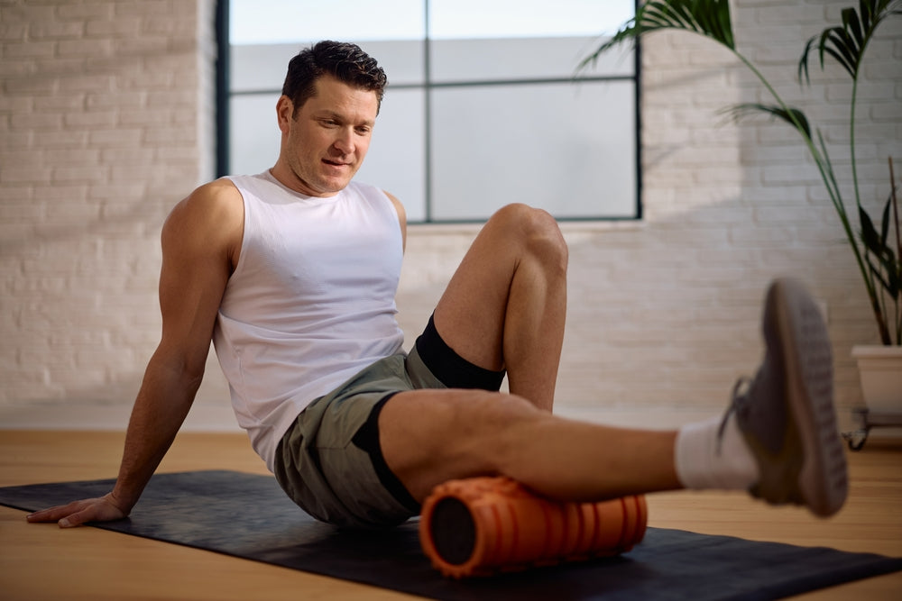 Mann trainiert mit Faszienrolle seine Beine