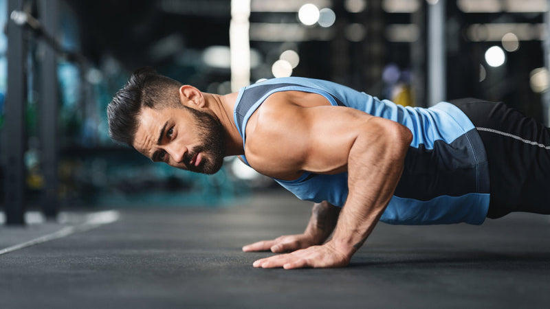 Mann trainiert Liegestütze im Fitnessstudio