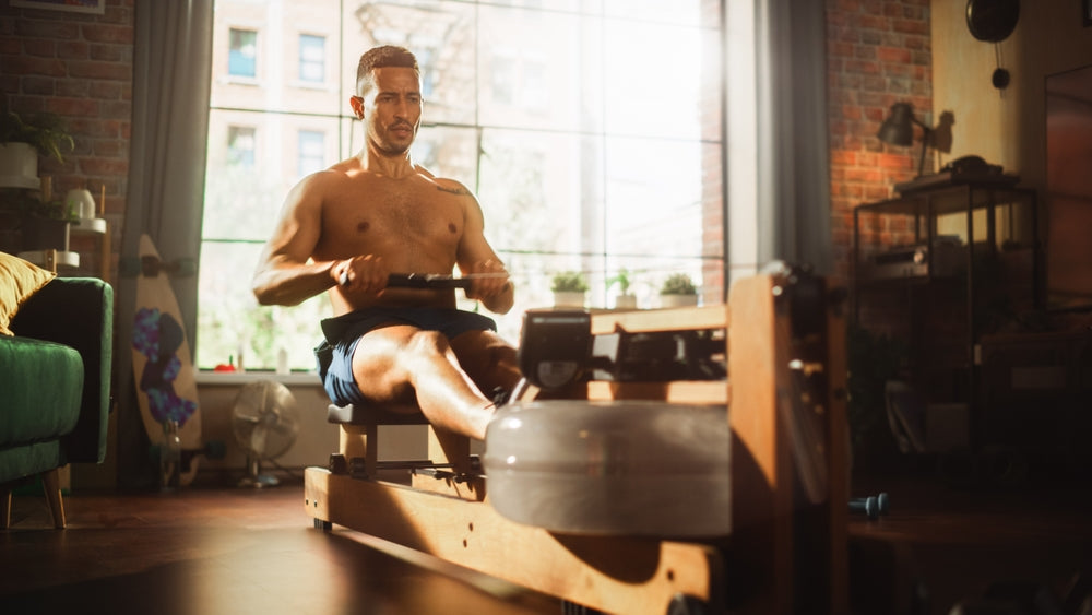 Mann trainiert mit Water Rower zuhause