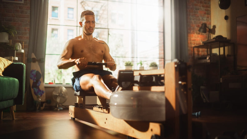 Mann trainiert mit Water Rower zuhause