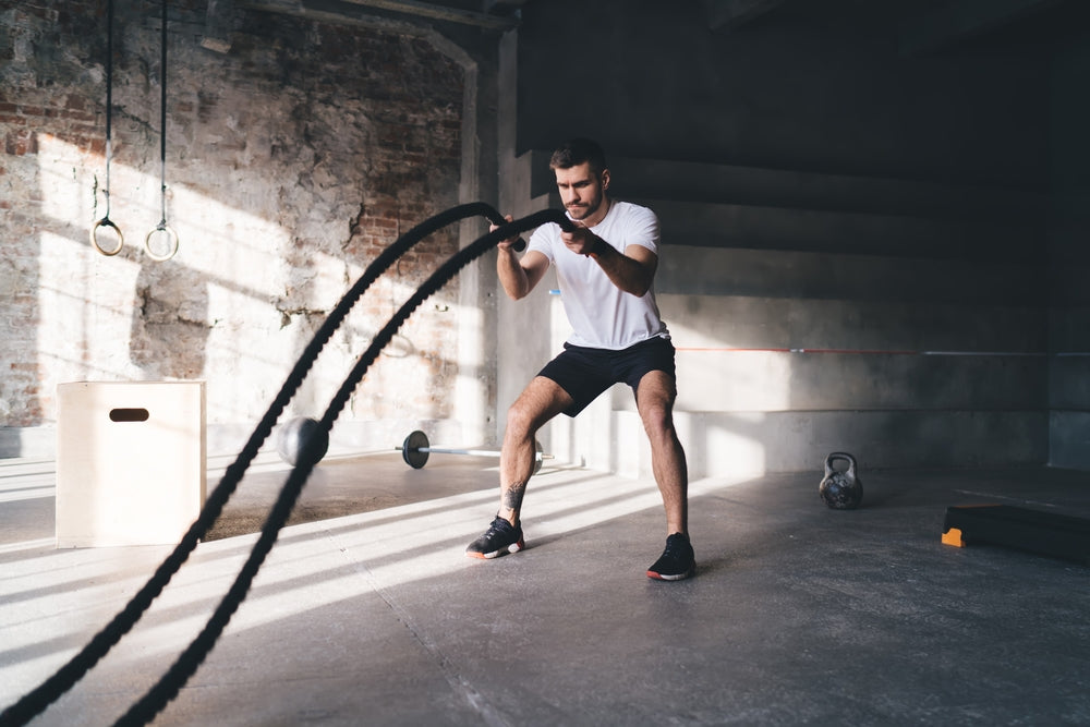 Mann trainiert mit Power Ropes im Fitnessstudio
